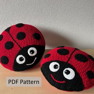 May include: Two crocheted ladybug pillows, one red with black spots and one black with red spots. Both have white eyes and a smiling mouth. The text "PDF Pattern" is visible below the pillows.