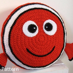 May include: Crochet pattern for a red and white fish pillow with black eyes and a smiling mouth. The pattern is available as a PDF download.