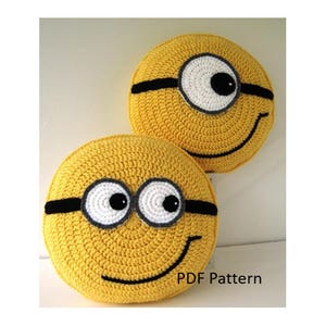 Könnte beinhalten: Zwei gehäkelte gelbe Minion-Kissen mit schwarzen Schutzbrillen und einem schwarzen Lächeln. Die Kissen haben weiße Augen mit schwarzen Pupillen. Der Text "PDF Pattern" befindet sich am unteren Rand des Bildes.