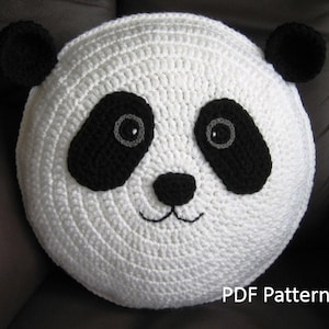 May include: White crocheted panda pillow with black eyes, nose, and ears. The pillow has a black and white panda face design. The text "PDF Pattern" is at the bottom of the image.