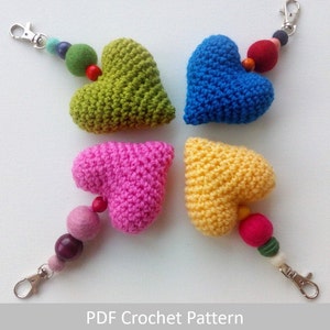 May include: Four crocheted heart-shaped keychains with colorful beads and metal key rings. The hearts are green, blue, pink, and yellow.