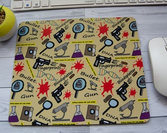 May include: A yellow mouse pad with a repeating pattern of crime scene related illustrations. The illustrations include a magnifying glass, a gun, a vial of purple liquid, a microscope, a bullet, a strand of DNA, and the words "Bloodsplatter", "Bullet", "Gun", "DNA", "Fingerprints", and "Crime Scene Do Not Cross".