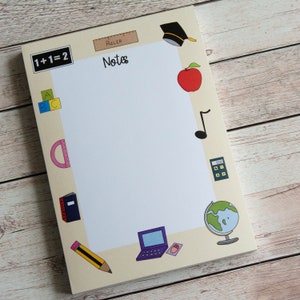 May include: A yellow notepad with a white lined interior and a border of school-themed illustrations. The illustrations include a ruler, a graduation cap, an apple, a music note, a calculator, a globe, a pencil, a protractor, a book, and a laptop. The text "Notes" is written in black cursive on the notepad. The text "1+1=2" is written in black on a yellow rectangle at the top left corner of the notepad.