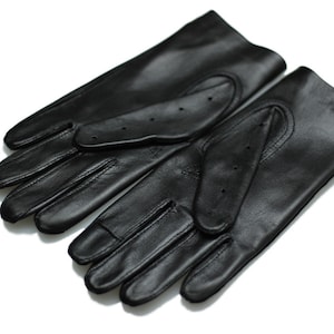 Könnte beinhalten: Ein Paar schwarze Leder-Fahrhandschuhe mit perforierten Fingerspitzen.