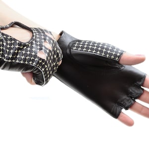 May include: A pair of black leather fingerless gloves with a gold and black geometric pattern. The gloves have a snap closure on the wrist.