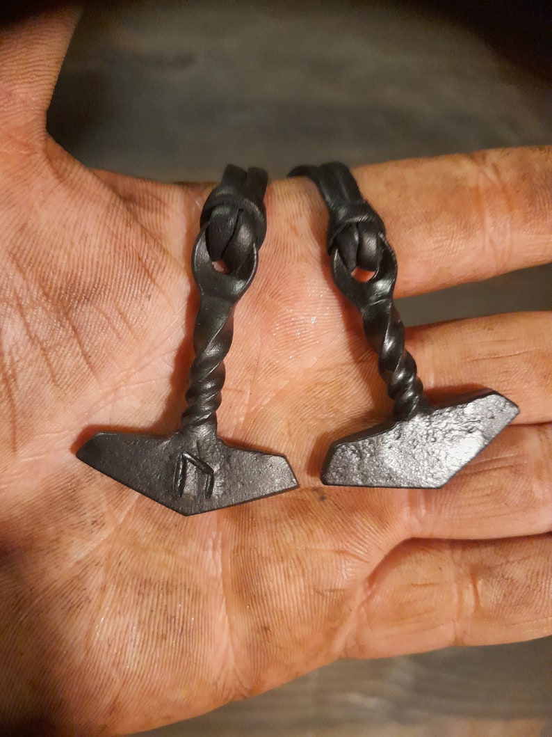 May include: Two black leather bracelets with a twisted metal hammer charm. Each charm has a rune symbol engraved on it.