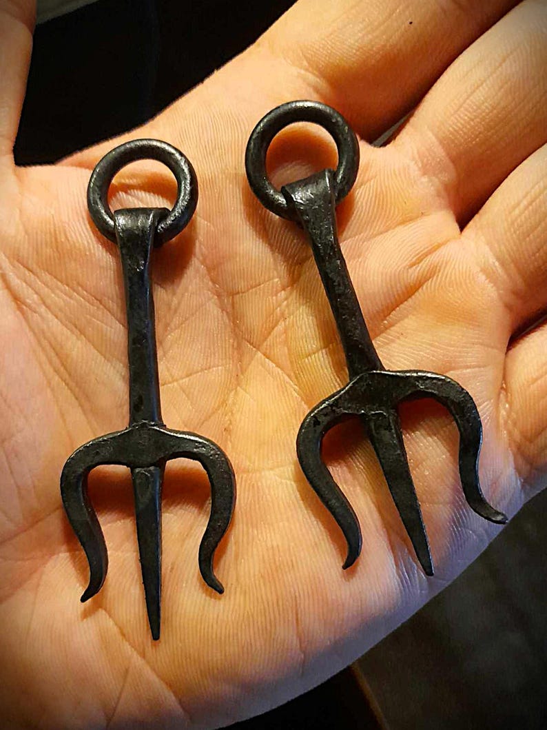 K&ouml;nnte beinhalten: Zwei schwarze Metalltridents mit einem Ring an der Oberseite jedes Griffs.