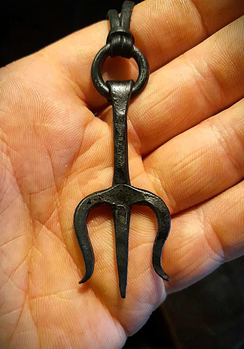 K&ouml;nnte beinhalten: Schwarzer Metall-Trident-Anh&auml;nger mit einem Lederband. Der Dreizack hat drei Zacken und einen Ring oben.