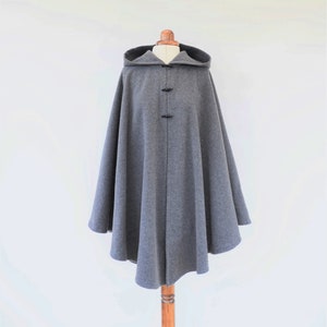 May include: A gray hooded cape with a rounded hem and black button closures.