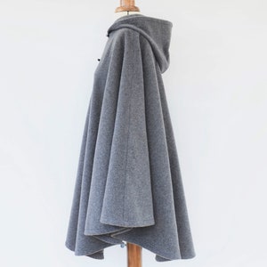 May include: Gray hooded cape with a long, flowing design. The cape is made of a soft, comfortable fabric and has a relaxed fit.