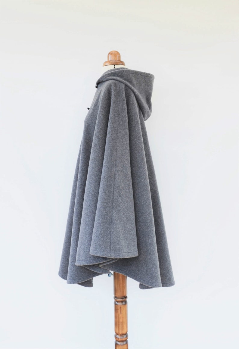 May include: Gray hooded cape with a long, flowing design. The cape is made of a soft, comfortable fabric and has a relaxed fit.