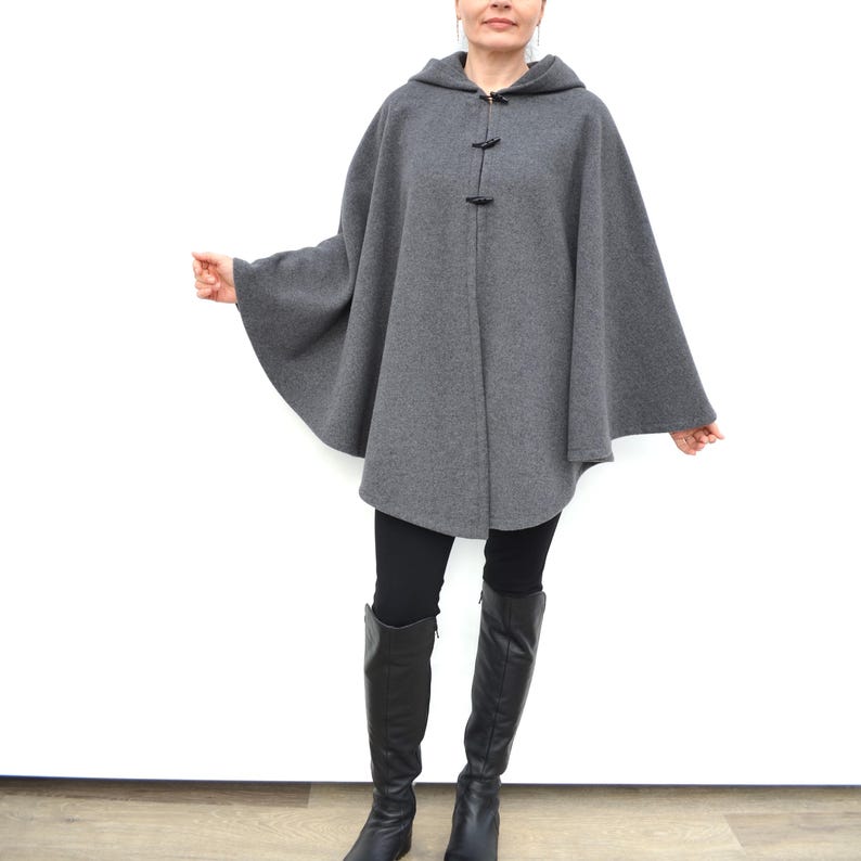 May include: A gray hooded cape with a long, flowing design. The cape has a zipper closure and two black toggle closures on the front.