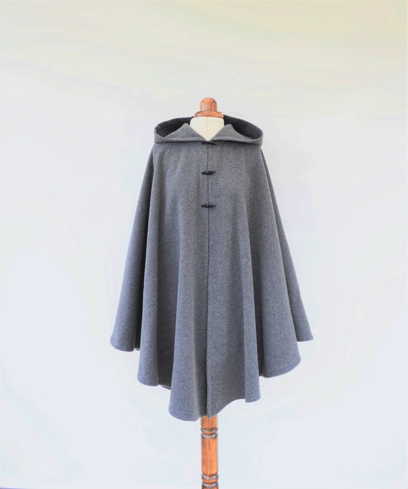 May include: A gray hooded cape with a rounded hem and black button closures.