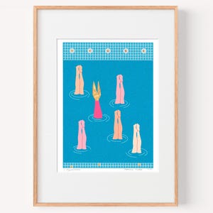 May include: Art print featuring a stylized illustration of figures in a pool. The figures are depicted with arms raised, in shades of pink, peach, and gold, against a blue background. The print is framed in a light wood frame.