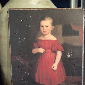 May include: A vintage painting of a young girl in a red dress holding a string attached to a small white lamb. The girl is standing on a patterned rug with red and gold accents.