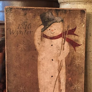 May include: A rustic wooden sign with a painted snowman wearing a black top hat and a red scarf. The sign has the text "1816 Wynter" and snowflakes in the background.
