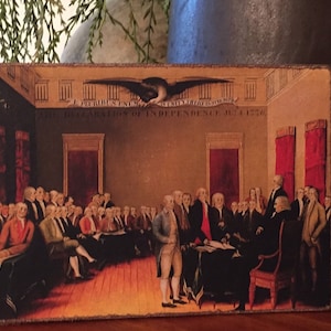 May include: A vintage-style painting depicting the signing of the Declaration of Independence. The painting shows a group of men in formal attire gathered around a table, with a bald eagle flying overhead. The text "IN CONGRESS JULY 4 1776" is visible at the top of the painting.