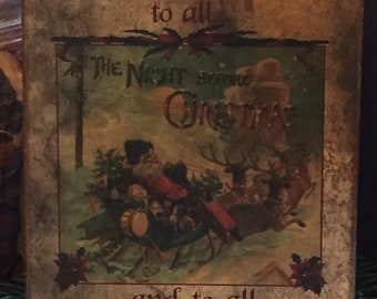 May include: A rectangular Christmas sign with the text "Merry Christmas to all and to all a Good Night!" in brown script. The center features an illustration of Santa Claus in a sleigh pulled by reindeer.