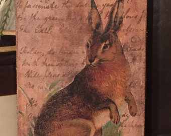 May include: A vintage-style wood sign with a brown rabbit illustration. The sign has a distressed, aged look and features handwritten text that reads "hem spring returns with tempting To fascinate the sul in the green The Carl bolet with trembling Will pleas cary (.."