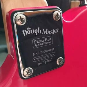 May include: A black plate with silver screws, attached to a red surface. The plate reads "The Dough Master" and "Pizza Hut Special Edition." The serial number and "Custom Built for Paul" are also visible.