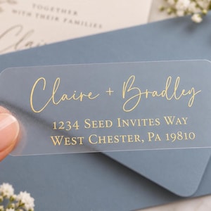 Può includere: Un'etichetta per indirizzi rettangolare semitrasparente con scritte in lamina d'oro. Il testo riporta Claire + Bradley, seguito dall'indirizzo 1234 Seed Invites Way, West Chester, PA 19810. L'etichetta ha angoli arrotondati e finitura satinata.