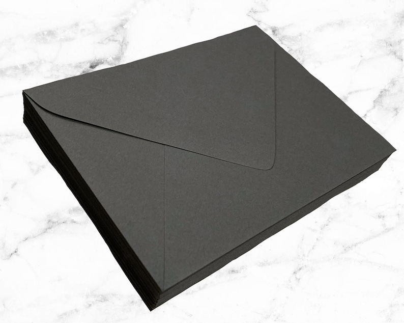 Pode incluir: Uma pilha de envelopes pretos, provavelmente para enviar cartas ou convites.
