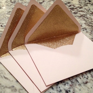May include: Three pink envelopes with gold glitter lining the flap.