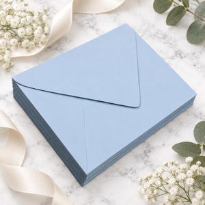 May include: A stack of light blue envelopes with a triangular flap design. The envelopes are arranged in a neat pile, showcasing a smooth, matte finish and a consistent rectangular shape, providing a clean and uniform appearance for stationery.