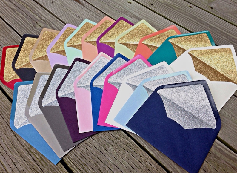 Pu&ograve; includere: Una variet&agrave; di buste con fodera in glitter dorato. Le buste sono di diversi colori, tra cui rosso, blu, verde, rosa e viola.