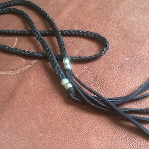 May include: A black braided leather necklace with silver beads and long tassels.