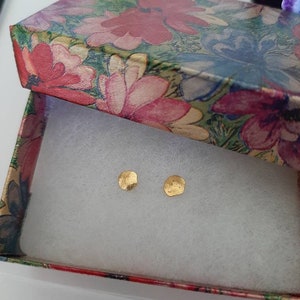 May include: Two small, gold, hammered, round earrings in a floral patterned gift box.