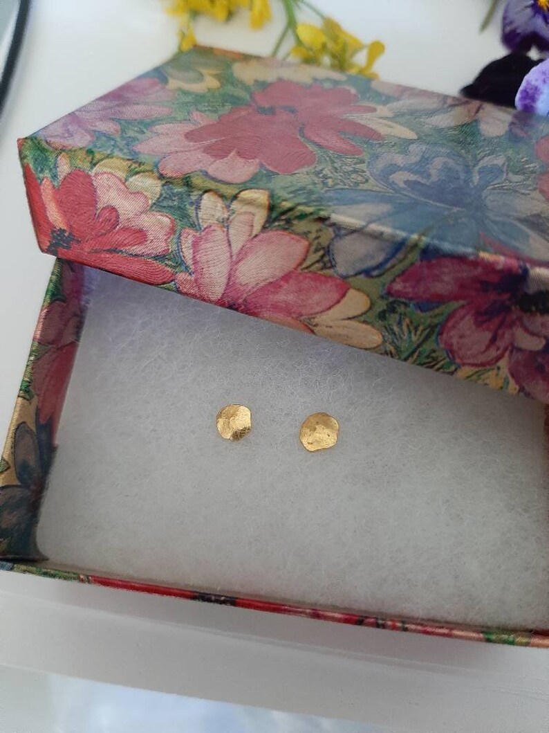 May include: Two small, gold, hammered, round earrings in a floral patterned gift box.