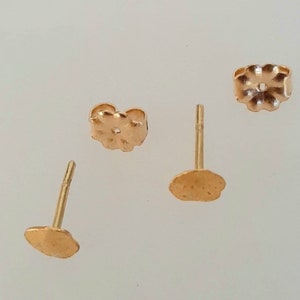 May include: Three gold-toned earring backs, two are round and one is a flower shape.