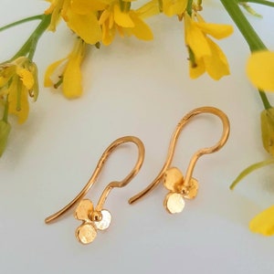 Pendientes artesanales de oro macizo de 24 quilates. Pequeños pendientes colgantes con forma de flor de oro puro de 24 quilates.