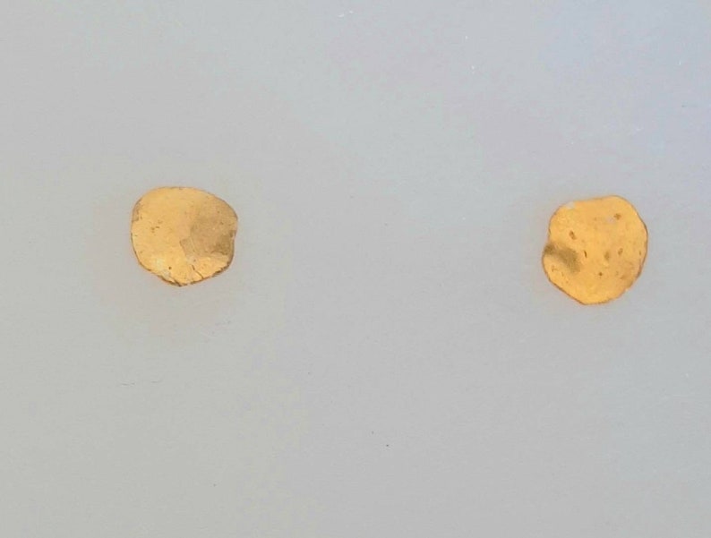 May include: Two small, irregularly shaped, gold-colored metal pieces on a white background.