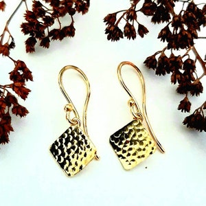 May include: A pair of gold hammered square earrings with a simple hook fastening.