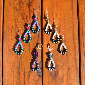 May include: Seven colorful beaded keychains with letter beads spelling out the words "WILL", "MIR", "MIR", "MIR", "WILL", "WILL", and "WS".