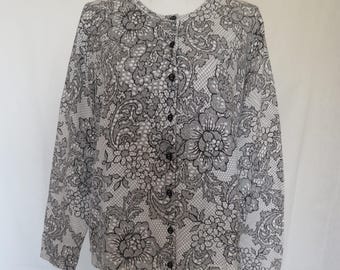 May include: A button-down blouse with a floral lace pattern in black and white. The long-sleeved top features a round neckline and black buttons down the front. The intricate design creates a delicate and elegant look.