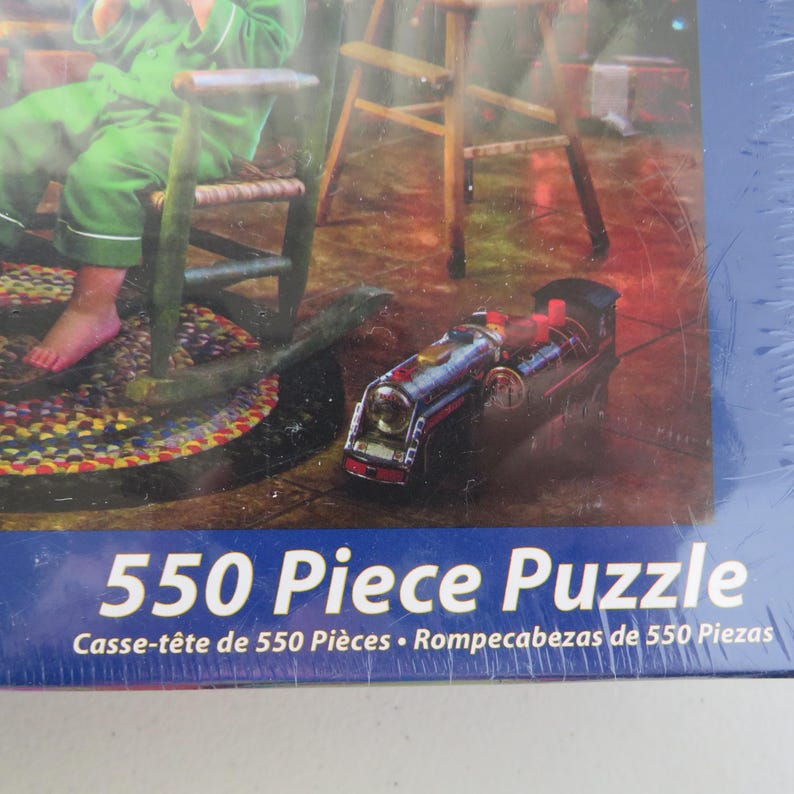 May include: A 550-piece puzzle box featuring a detailed illustration of a toy train, a rocking chair, and a child in green pajamas. The puzzle box has text that reads "550 Piece Puzzle".