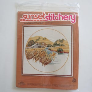 May include: Sunset Stitchery embroidery kit featuring a country scene with a farmhouse, wheat field, and river. The kit is titled "Summer Wheat Fields" and is designed for a 10-inch round frame.