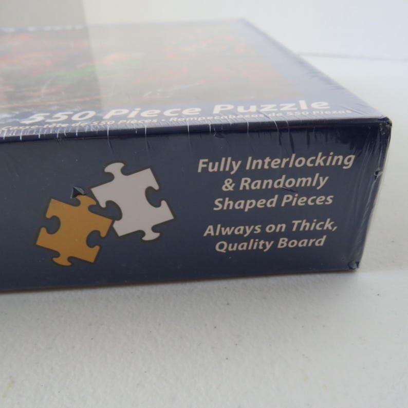 May include: A boxed 550-piece puzzle. The box is dark blue with white text that reads "Fully Interlocking & Randomly Shaped Pieces Always on Thick, Quality Board." Two puzzle pieces are shown in gold and white.