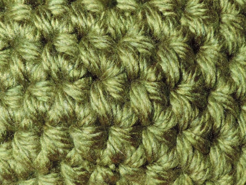 May include: Close-up of a green crocheted fabric with a textured, woven pattern.