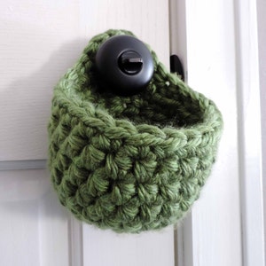 May include: A green crocheted hanging basket with a black hook.