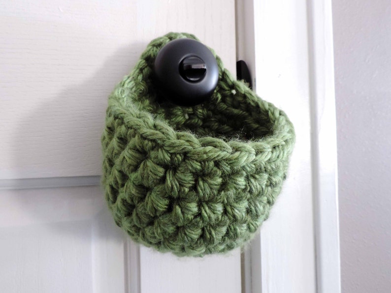 May include: A green crocheted hanging basket with a black hook.