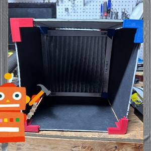 May include: A black box with a white filter inside. The box is made of cardboard and has red and blue corner pieces. The filter has a white label with the text "14+14+1".