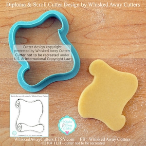 May include: A blue plastic cookie cutter shaped like a scroll with a decorative flourish at the top. The cutter is on a wooden surface next to a cookie cut out with the same shape. The text "Cutter design copyright protected by Whisked Away Cutters Cutter not to be recreated under U.S. & International Copyright Law" is visible in the image.
