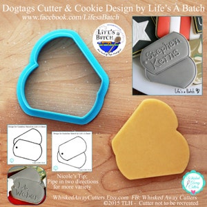 May include: A blue plastic cookie cutter shaped like a dog tag. The cutter is on a wooden surface. A gray cookie decorated with the text "Stephen Kerns" is shown in the background. The text "Life's a Batch" is also visible in the image.