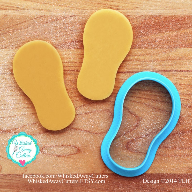 May include: A blue plastic cookie cutter shaped like a flip-flop on a wooden surface with two yellow cookie dough flip-flops.  The cookie cutter is for making flip-flop shaped cookies.  Design &copy;2014 TLH