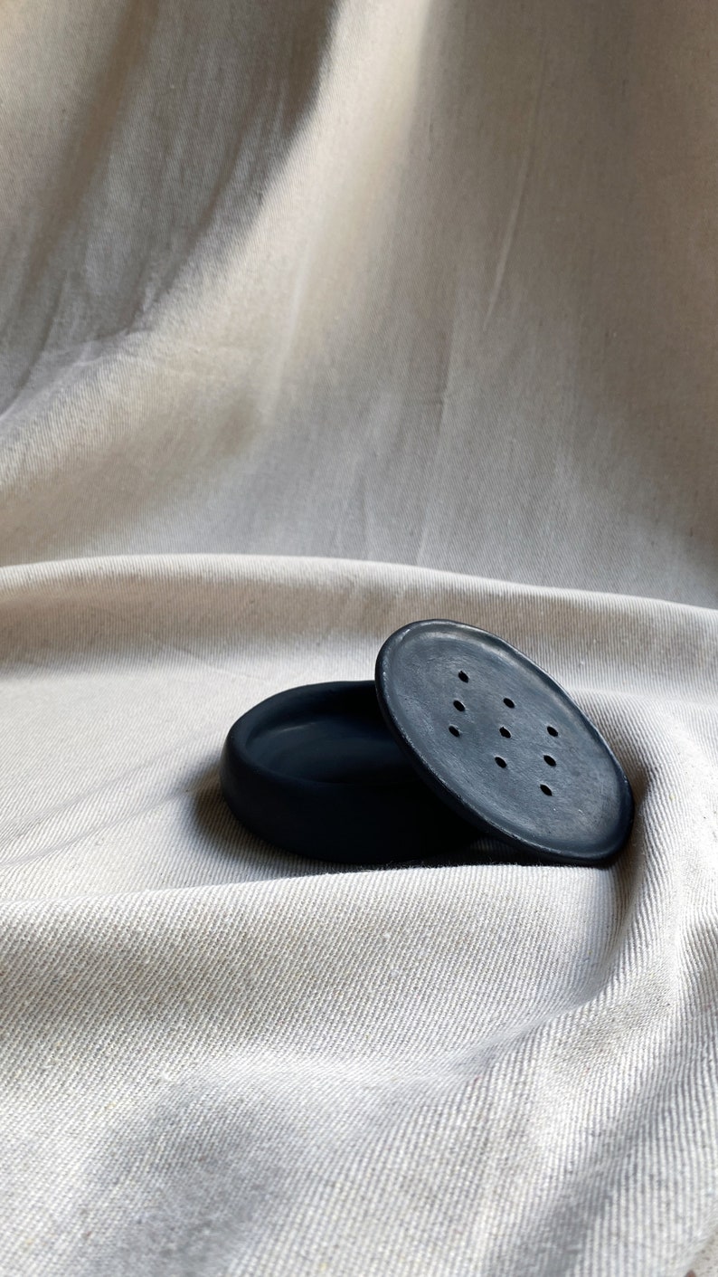 May include: A black ceramic soap dish with a lid. The lid has small holes for drainage.