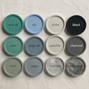 May include: Twelve round concrete coasters in various colours and patterns, including black, white, sage, mint, charcoal, sky blue, speckled, and marble. The coasters are labelled with their names.